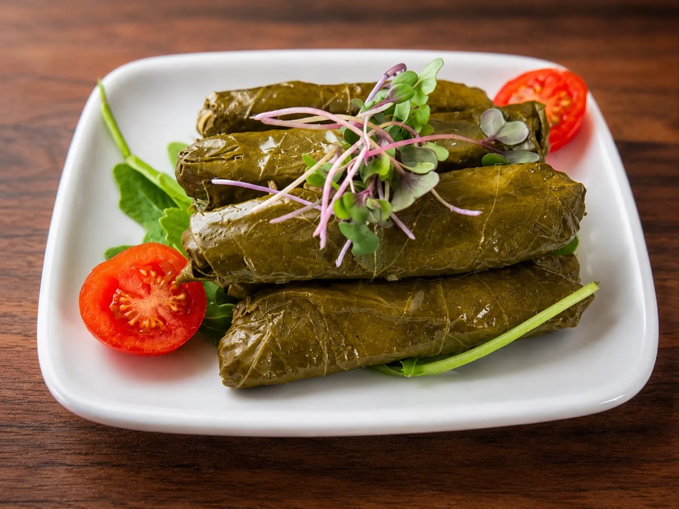 Hand-rolled stuffed grape leaves dolma with tomato and greens